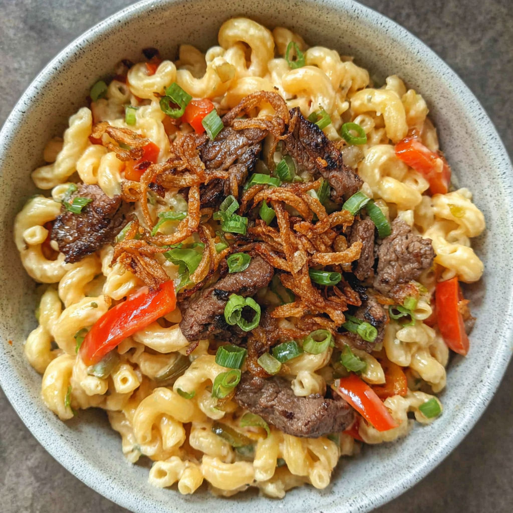 A bowl of mac and cheese with meat and vegetables.