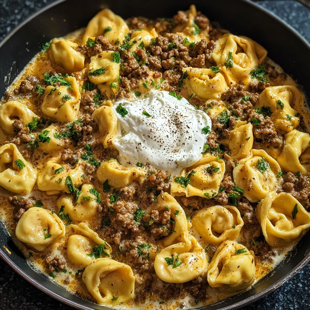 A plate of pasta with meat and cheese on top.