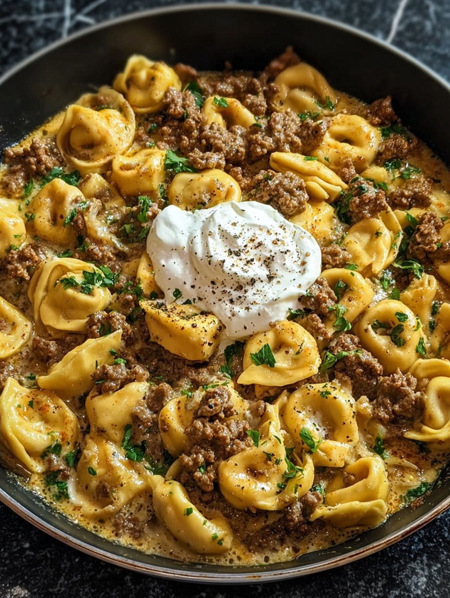 A bowl of pasta with meat and cheese on top.