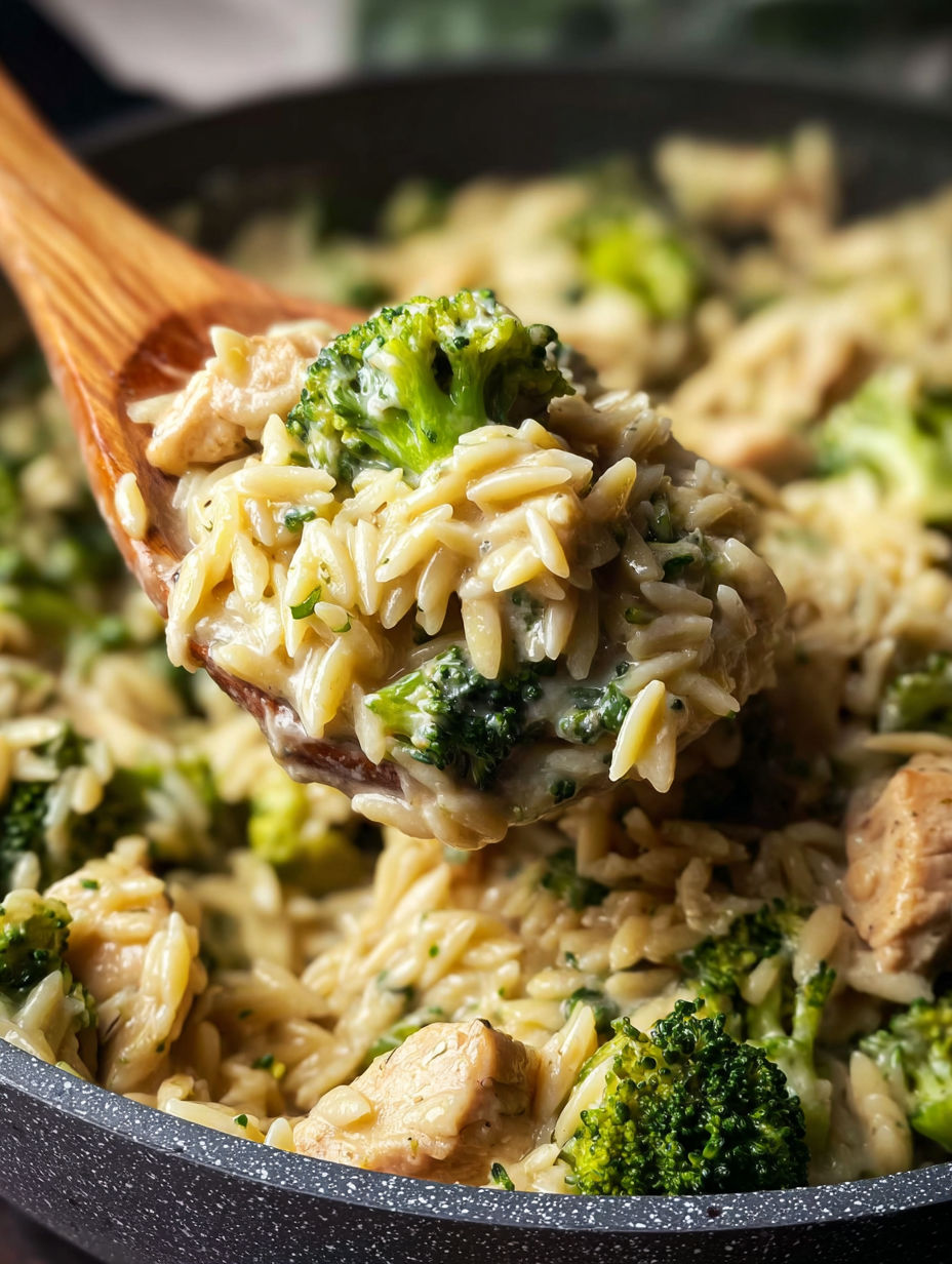 A wooden spoon is in a bowl of rice, broccoli, and chicken.