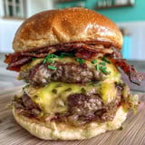 A close up of a burger with bacon and cheese.