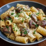 A bowl of pasta with meat and cheese.