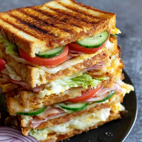 A stack of sandwiches with lettuce, tomato, and cucumber.