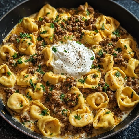 A plate of pasta with meat and cheese on top.
