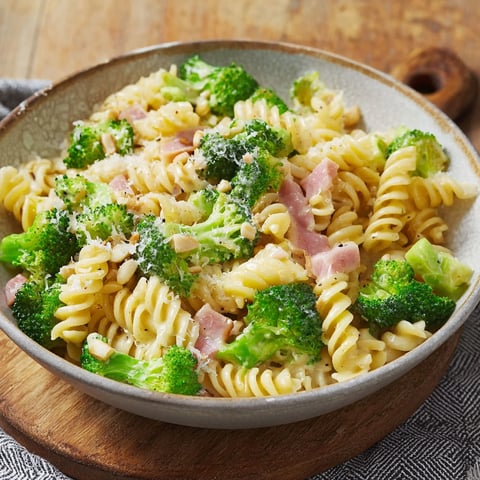A bowl of pasta with broccoli and ham.