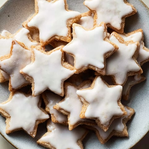 A plate of cookies with white icing and star shapes.