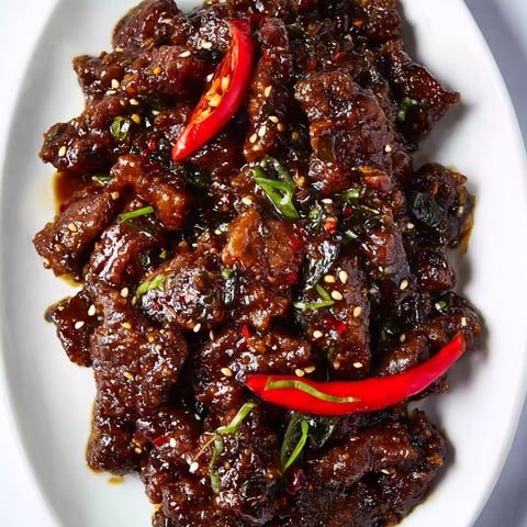A plate of Mongolian beef with red peppers.
