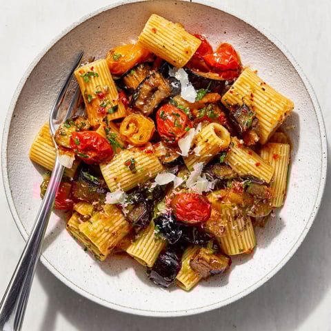 A bowl of pasta with tomatoes and mushrooms.