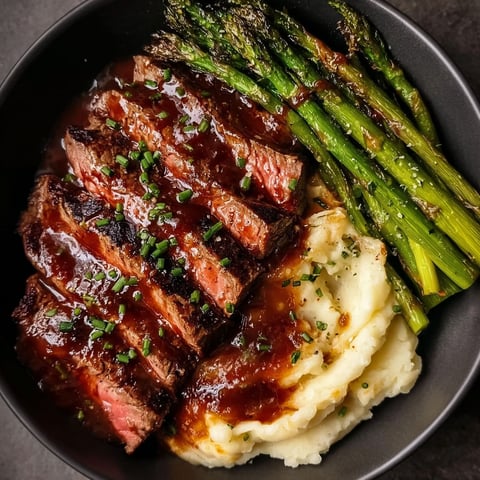 A plate of food with steak, potatoes and asparagus.