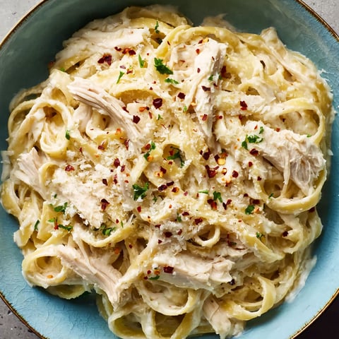 A bowl of pasta with chicken and cheese.
