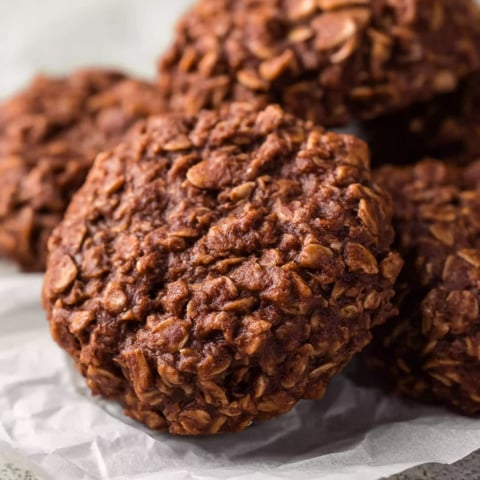 A plate of brown cookies with nuts on top.